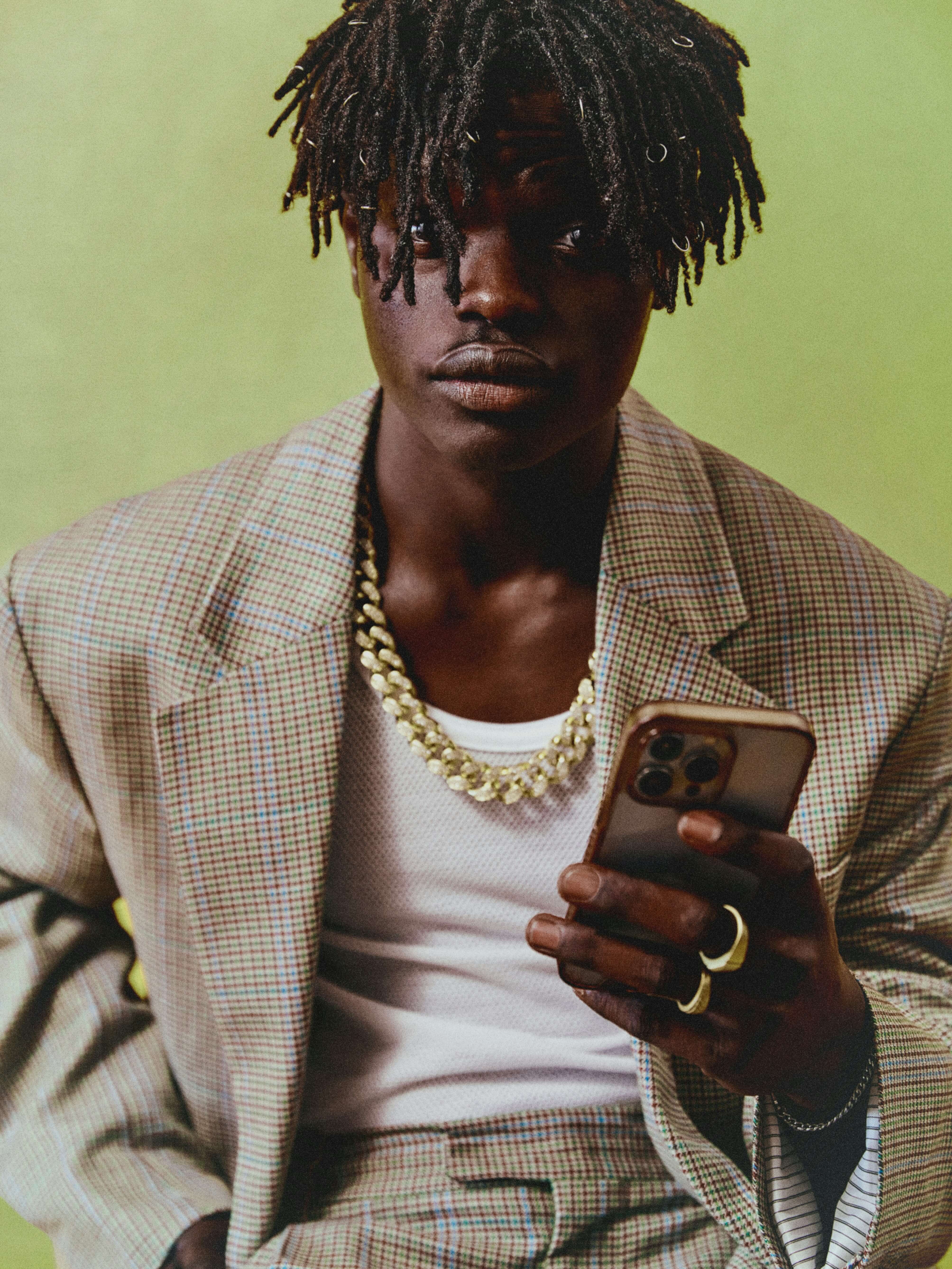 Fotografia com estética vintage de um homem preto com cabelo black sentado em uma cadeira de escritório enquanto fala em um telefone.